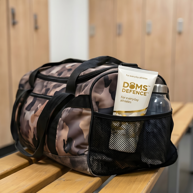 Camouflage duffel bag with 'Doms Defence' product and water bottle in a locker room setting